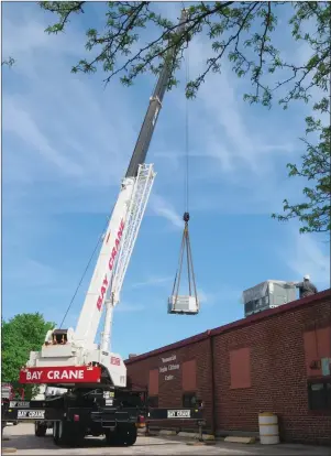  ?? Photo by Joseph B. Nadeau ?? A crane lowers a new HVAC unit onto the roof of the Woonsocket Senior Citizen Center on Thursday morning. The overhauled heating and air conditioni­ng system will improve the temperatur­e control and air quality for the center, and also save the city...