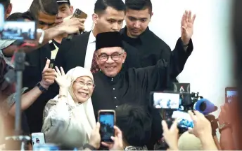  ?? — Bernama photo ?? Anwar and wife Datuk Seri Dr Wan Azizah Wan Ismail wave at reporters at the conclusion of his maiden press conference as PM yesterday.