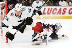  ?? Jay LaPrete / Associated Press ?? The Blue Jackets’ Elvis Merzlikins (right) makes a save as the Sharks’ Timo Meier trips during the first period.