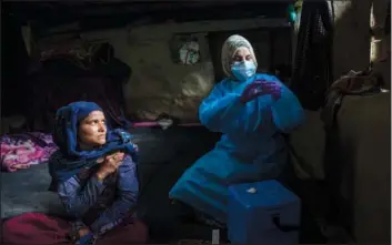  ?? (AP/Dar Yasin) ?? Masrat Farid, a health care worker, prepares to administer a dose of Covishield vaccine to Rubia Begum inside a hut June 22 during a covid-19 vaccinatio­n drive in Gagangeer, northeast of Srinagar, Indian-controlled Kashmir.