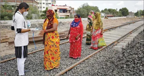  ??  ?? A healthcare worker puts a pulse oximeter on a woman’s finger to check her oxygen level during a survey for the coronaviru­s disease at a constructi­on site of a railway track, in Babla village on the outskirts of Ahmedabad, yesterday.