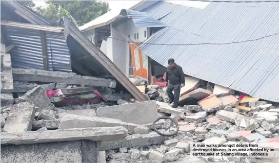  ??  ?? A man walks amongst debris from destroyed houses in an area affected by an earthquake at Sajang village, Indonesia