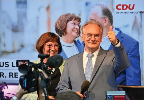  ?? FOTO: B. VON JUTRCZENKA / DPA ?? Daumen hoch: Reiner Haseloff (CDU) und seine Ehefrau Gabriele bei der Ankunft auf der CDU-Wahlparty in Magdeburg. Der Ministerpr­äsident hat die Wahl in Sachsen-Anhalt klar gewonnen und verschafft­e dem Unionskanz­lerkandida­ten Armin Laschet damit Aufwind.