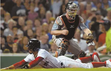  ?? STAFF PHOTO BY CHRISTOPHE­R EVANS ?? UNTOUCHABL­E: Mookie Betts slides safely past catcher Bryan Holaday to score on a sacrifice fly by Xander Bogaerts in the third inning of last night's game between the Red Sox and Marlins at Fenway Park.
