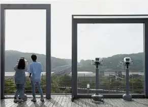  ??  ?? The land beyond: A couple looking at North Korea from an observatio­n deck near the demilitari­sed zone in Paju, South Korea. — Reuters