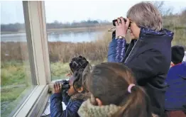  ?? — AP ?? Britain’s Prime Minister Theresa May looks through binoculars as she watches birds from inside a bird hide with schoolchil­dren at the London Wetland Centre in London on Thursday. Ms May will launch her 25- year environmen­t plan at the London Wetland...