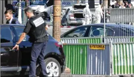  ?? THIBAULT CAMUS / AP ?? Police officers examine the attacker’s car (center rear) after a man rammed into a police convoy on the Champs Elysees Avenue in Paris on Monday. France’s interior minister says the threat of terrorism remains very high in the country.