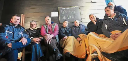  ??  ?? Iron-willed protest: Workers of Zenica Ironworks sitting in a room during a hunger strike in Zenica. (Below) A worker blocking one of the main roads in Bosnia to protest against social conditions. — AFP