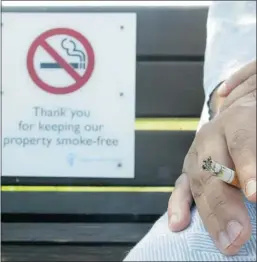  ?? Calgary Herald/files ?? A patient has a cigarette next to a no-smoking sign on a bench outside Peter Lougheed Hospital. Reader says AHS must stop patients from smoking on the premises for the sake of their own and other patients’ health.