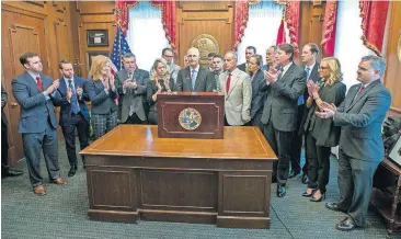  ?? [MARK WALLHEISER/AP PHOTO] ?? Flanked by Florida legislator­s and family members of victims of the Marjory Stoneman Douglas school shooting, Florida Gov. Rick Scott is applauded before he signs the Marjory Stoneman Douglas Public Safety Act, Friday in the Governor’s office at the...