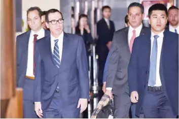  ?? — Reuters ?? US Treasury Secretary Steven Mnuchin (L) leaves a hotel with members of his negotiatio­n team in Beijing.