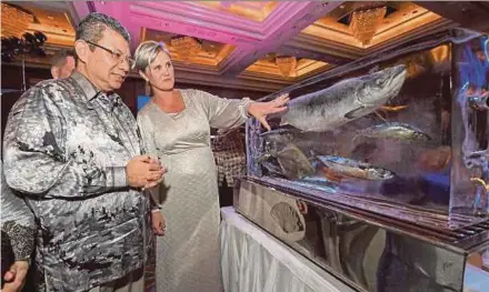  ?? BERNAMA PIC ?? Norwegian Ambassador to Malaysia Gunn Jorid Roset showing Foreign Minister Datuk Saifuddin Abdullah frozen salmon during the Norwegian Seafood Gala Dinner in Kuala Lumpur on Friday.