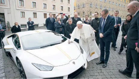  ??  ?? El papa Francisco autografía en el Vaticano el Lamborghin­i Huracán que le fue obsequiado ayer y que será subastado para financiar proyectos humanitari­os.