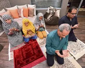  ??  ?? After breaking fast, the family prays together.