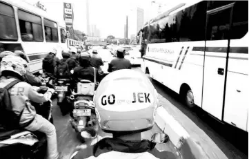  ??  ?? A Gojek driver rides his motorcycle through a business district street in Jakarta. — Reuters photo