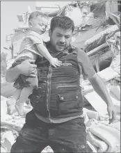  ??  ?? A Syrian man carries a baby after removing him from the rubble of a destroyed building following a reported air strike in the Qatarji neighbourh­ood of the northern city of Aleppo on Tuesday.