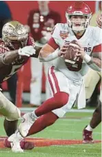  ?? STEPHEN M. DOWELL/ORLANDO SENTINEL ?? Oklahoma quarterbac­k Dillon Gabriel, who will meet his former team UCF on Oct.
21 in Norman, scrambles away from FSU defenders Jared Verse, left, and Derrick McLendon II during the Cheez-It Bowl last season at Camping World Stadium.