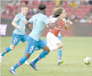  ??  ?? Matteo Guendouzi (right) of Arsenal runs with the ball past Atletico Madrid players during their Internatio­nal Champions Cup match in Singapore in this July 26 file photo. — AFP photo