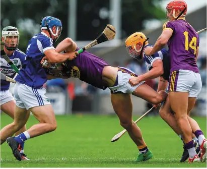 ??  ?? Wexford’s Harry Kehoe (centre) has little room to manoeuvre as he is tackled by Lee Cleere and Charles Dwyer of Laois