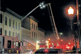  ?? JOELLE KOVACH/ EXAMINER ?? City firefighte­rs battle a fire at 372 George St. N. in downtown Peterborou­gh early Friday morning. Flames were shooting out of the roof when they arrived late Thursday night.