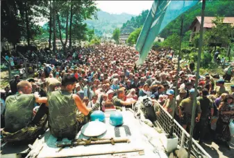  ?? Associated Press 1995 ?? Muslim refugees from Srebrenica surround Dutch U.N. peacekeepe­rs in 1995 in the nearby village of Potocari. Some 8,000 Muslim men and boys were killed by Bosnian Serb forces.