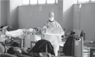  ?? LUCA BRUNO/AP ?? TOP: Tanya Castagna, a Baltimore native and Hopkins-trained nurse, lives in Italy and works in a university hospital there. ABOVE: Medical staff work at one of the emergency structures that were set up to ease procedures at the Brescia hospital in northern Italy, where coronaviru­s has hit hard.