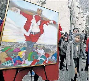  ??  ?? CHRISTMESS: This painting of Santa being crucified, meant as a critique of commercial­ism, spreads holiday jeer outside St. Patrick’s Cathedral on Sunday.