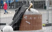  ?? DAVID KEYTON / AP ?? A black cloth used to hide the vandalized statue of Zlatan Ibrahimovi­c uncovers a bronze foot from the block of stone, outside the stadium of Malmo’s soccer team in Sweden. The statue is undergoing repairs.