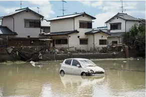  ?? — AFP ?? Immobile: A car sitting in water after the area was devastated by flooding in Mabi, Okayama prefecture.