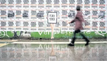  ??  ?? En la Avenida Paulista, en Sao Paulo, hay un muro lleno de carteles en contra del presidente de Brasil, Michel Temer, quien quedó mal parado tras nuevas confesione­s en las que señalan que recibió sobornos.