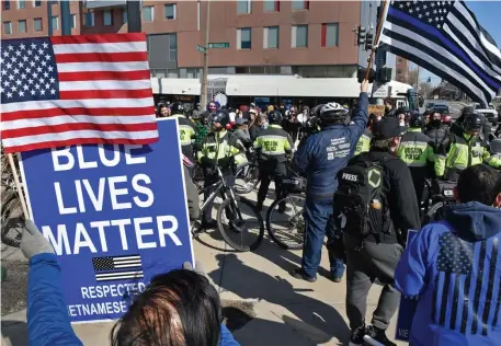  ?? CHRIS CHRISTO PHOTOS / HERALD STAFF ?? OPPOSITE SIDES: Police keep a line between people rallying in support of law enforcemen­t and counterpro­testers in front of Boston Police headquarte­rs on Saturday. Below, a person holds a sign and, below left, people use bullhorns to protest the Blue Lives Matter rally.