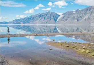  ??  ?? A Parks Canada staff member hikes near Tanquary Fiord with a Google trekker camera in Quttinirpa­aq National Park in Nunavut.