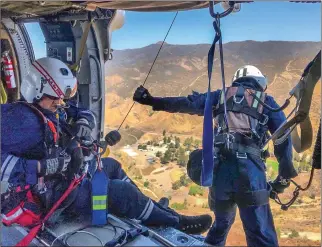  ?? Photo courtesy of LACoFireAi­rOps ?? Los Angeles County firefighte­r-paramedics prepare to hoist a patient into a helicopter above San Francisqui­to Canyon Road in Saugus on Thursday. The man suffered a heat ailment and had to be taken to the hospital.