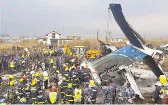  ?? Prakash Mathema / AFP / Getty Images ?? Rescue workers gather around the wreckage of the US-Bangla Airlines plane that crashed Monday in Kathmandu, Nepal’s capital. There were 67 passengers and four crew on board.