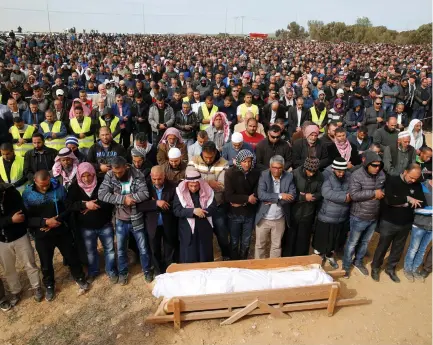  ?? (Reuters) ?? FRIENDS AND relatives pray next to the body of Yacoub Abu al-Kaeean during his funeral in the Beduin village of Umm al-Hiran.