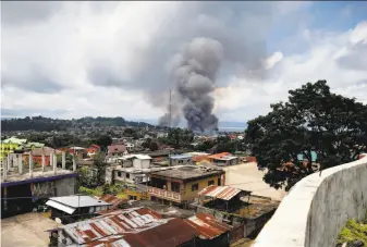  ?? Bullit Marquez / Associated Press ?? Fires burn houses after air strikes by Philippine bombers intended to retake control of the city of Marawi from militants. Residents raised white flags to avoid being attacked.