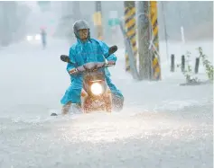  ??  ?? A motorcycli­st attempts to ride through floodwater­s, as Typhoon Nesat hits Pingtung county in southern Taiwan. — AFP photo