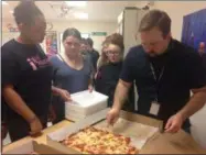 ?? JORDANA JOY — THE MORNING JOURNAL ?? Longfellow Middle School, 305 Louisiana Ave. in Lorain, sixth-grade teacher Martin Heberling III, right, passes out pieces of Campana’s Cafe pizza for a tasting party as a reward for improved state test grades May 16.