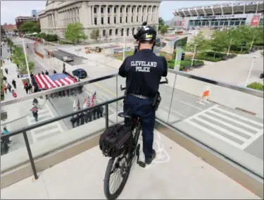  ?? JONATHAN TRESSLER — THE NEWS-HERALD ?? A Cleveland Police Department Officer on bicycle detail snaps a mobile-phone photo from above the convention center as the big flag passes beneath on Lakeside Avenue during the 32nd annual Greater Cleveland Peace Officers Memorial Parade and Memorial...