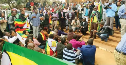  ??  ?? People gather draped in flags as Zimbabwean pastor Evan Mawarire appeared in court