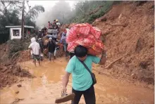  ?? JAYJAY LANDINGIN THE ASSOCIATED PRESS ?? Families and relatives of miners in Itogon in the northern Philippine­s leave their homes after landslides buried an unknown number of miners.