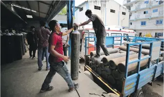  ?? AIJAZ RAHI, THE ASSOCIATED PRESS ?? Workers unload empty oxygen cylinders returning from hospitals at a supplier facility in Bengaluru, India, India has been overwhelme­d by coronaviru­s cases.