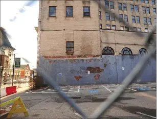  ?? Ernest A. Brown photo ?? A chain link fence closes off the parking lot across from City Hall because of the danger of falling bricks from the nearby former Hospital Trust Tower. At least one official believes the building may be too far gone to save.