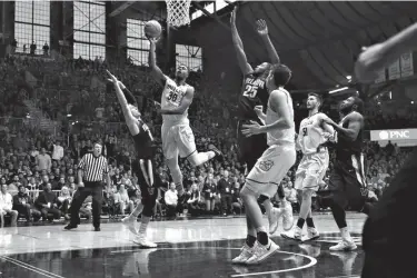  ?? Associated Press ?? n Butler forward Kelan Martin (30) shoots between Villanova defenders Donte DiVincenzo (10) and Mikal Bridges (25) in the first half of an NCAA college basketball game Saturday in Indianapol­is.