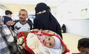  ?? — AFP ?? In need of aid: A Yemeni woman carrying her ill baby as they wait to travel abroad via a UN-sponsored humanitari­an air bridge at the Health Ministry headquarte­rs in Sanaa.