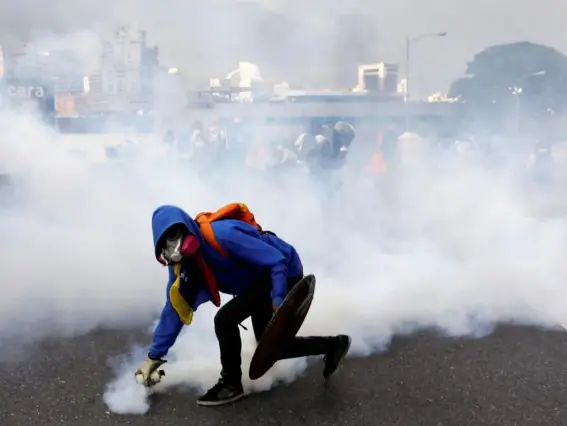  ??  ?? A demonstrat­or throws back a tear gas grenade at the riot police while rallying against Venezuela's President Nicolas Maduro (Reuters)