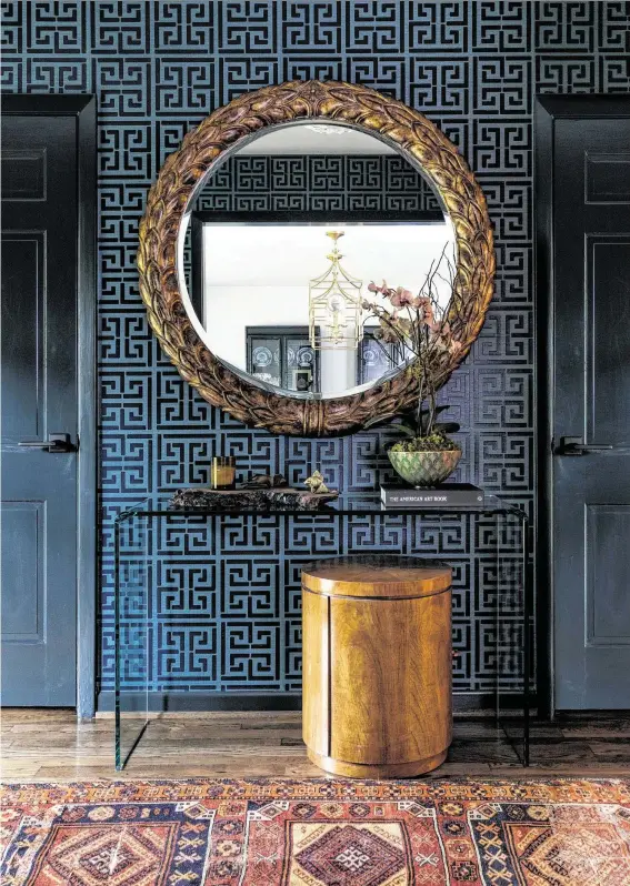 ?? Photos by Julie Soefer ?? Harlan and Cynthia Lane’s Asian-inspired foyer features vinyl-on-grasscloth wallpaper, a gold-framed mirror and Persian rug.