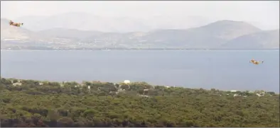  ?? The Associated Press ?? Firefighti­ng planes fly over the trees near the fire damaged village of Neos Voutzas near Athens, Tuesday. Twin wildfires raging through popular seaside areas near the Greek capital have torched homes, cars and forests, authoritie­s said.