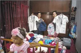  ?? Ramon Espinosa Associated Press ?? THE ROLO GONZÁLEZ sisters Merlyn, left, and Melanie pack supplies in Havana in December before migrating, with Melanie’s baby, from Cuba to the U.S.