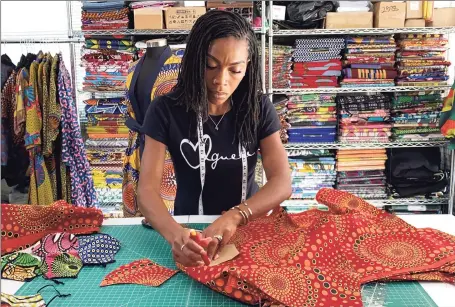  ?? Associated Press ?? Iguehi James, an Oakland, Calif., fashion entreprene­ur, cuts fabric to make a face mask she sells through her apparel company Love Iguehi. She received a $5,000 grant from the Oakland African American Chamber of Commerce’s “Resiliency Fund,” which seeks to help Black-owned businesses stay afloat during the coronaviru­s pandemic.